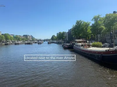 a river with boats docked next to the river amstration at JoyJoyJoy the Red Sun ecolicious studio in the historic Canalhouse Tropics at the Canals from 1729 in Amsterdam