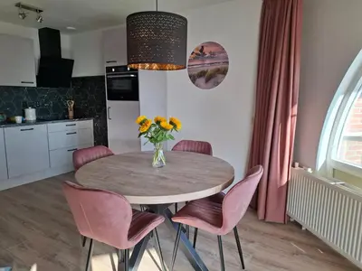 a dining room table with pink chairs and a vase of flowers at Residenz Polderblick Burgerbrug in Burgerbrug