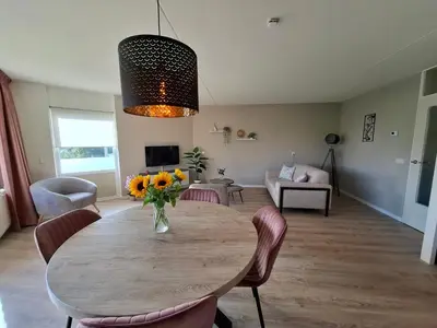 a dining room table with chairs and a vase of flowers at Residenz Polderblick Burgerbrug in Burgerbrug