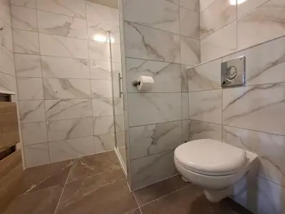a bathroom with a toilet and a marble wall at Residenz Polderblick Burgerbrug in Burgerbrug