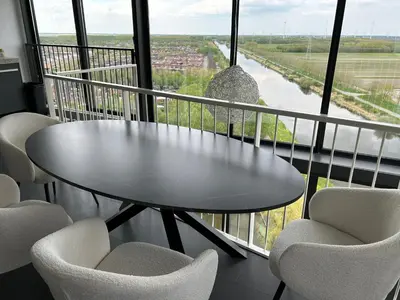 a table and chairs in a balcony with a view of a river at Luxe Penthouse Met Panorama Uitzicht Op Natuur in Almere
