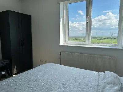 a bedroom with a bed and a large window at Luxe Penthouse Met Panorama Uitzicht Op Natuur in Almere