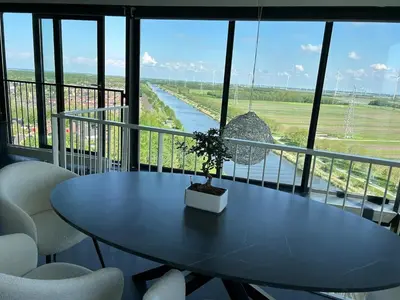 a table and chairs on a balcony with a view of a river at Luxe Penthouse Met Panorama Uitzicht Op Natuur in Almere