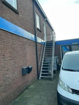 a stairway leading up to a brick building with a car at Have a nice stay! - Ruim appartement de Molen in Noordwijk