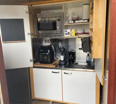 a small kitchen with white cabinets and a microwave at 1-2 pp ROOM AMS Airport great view lake in Roelofarendsveen