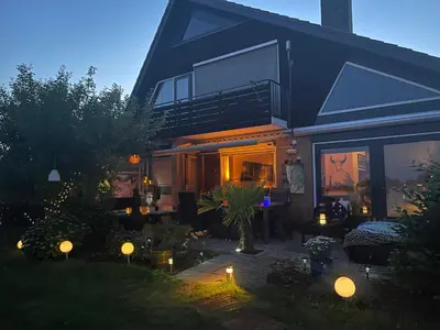 a house with a patio with lights in the yard at 1-2 pp ROOM AMS Airport great view lake in Roelofarendsveen