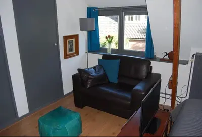 a living room with a black leather couch and a window at Apartement with terras in Amsterdam Noord in Amsterdam