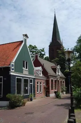 a large house with a green roof and a church at Apartement with terras in Amsterdam Noord in Amsterdam