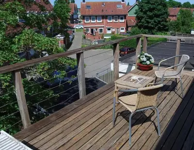 a wooden deck with a table and chair on a balcony at Apartement with terras in Amsterdam Noord in Amsterdam