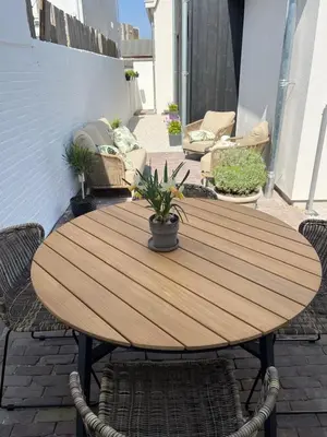 a wooden table and chairs on a patio at 't Voorhuys Noordwijk aan Zee- tuin en gratis parkeren in Noordwijk