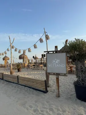 a sign on the beach in front of a restaurant at 't Voorhuys Noordwijk aan Zee- tuin en gratis parkeren in Noordwijk