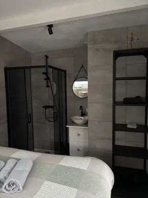 a bedroom with a bed and a bathroom with a sink at BeachBreak Guesthouse in Noordwijk