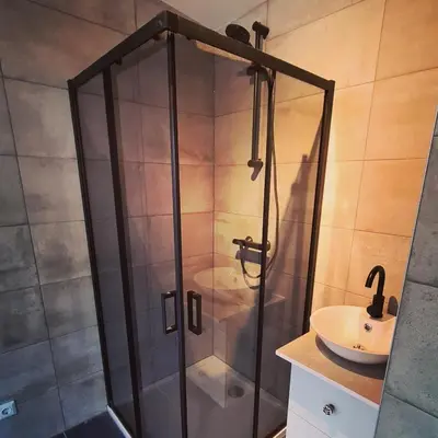 a shower with a glass door next to a sink at BeachBreak Guesthouse in Noordwijk