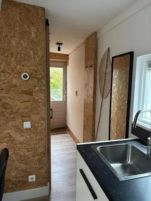 a kitchen with a sink and a door to a room at BeachBreak Guesthouse in Noordwijk