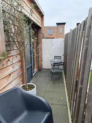 a patio with a table and a fence at BeachBreak Guesthouse in Noordwijk