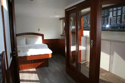 a small bedroom with a bed and a glass door at Prinsenboot in Amsterdam