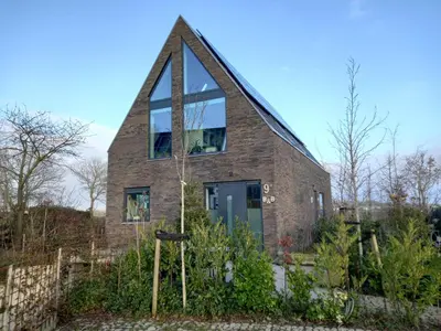 a brick house with a large window on it at gastenverblijf Bij de Dijk in Warmenhuizen
