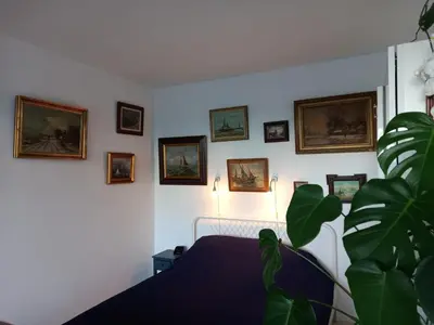 a bedroom with a bed and pictures on the wall at gastenverblijf Bij de Dijk in Warmenhuizen
