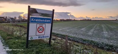 a sign in a field next to a field of crops at gastenverblijf Bij de Dijk in Warmenhuizen