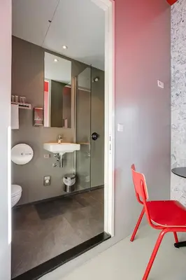 a bathroom with a red chair and a sink at ClinkNOORD Hostel in Amsterdam