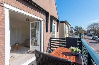 a patio with a wooden table and chairs on a balcony at Boutique Pension Bennekom - Studio's & Apartment in Zandvoort