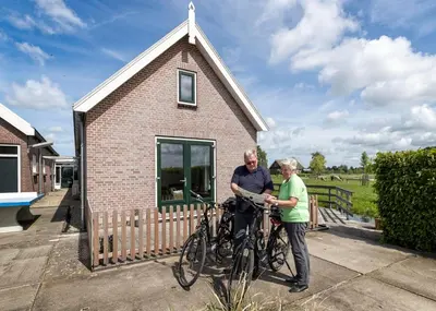 a man and woman standing with their bikes outside a house at Zaanse Rietveld Logies in Alphen aan den Rijn