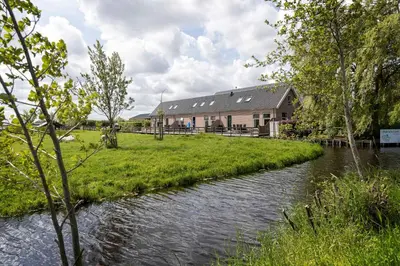 a house with a river in front of it at Zaanse Rietveld Logies in Alphen aan den Rijn