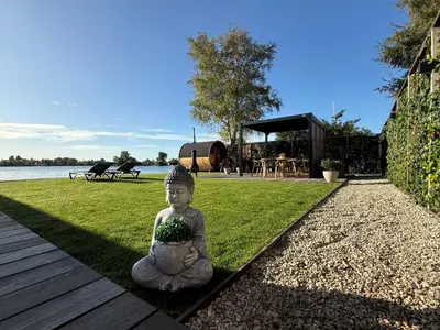 a statue of a buddha sitting on the grass at Villa Perla Mare - Sauna Experience - On a lake near Amsterdam in Vinkeveen