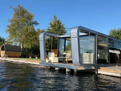 a glass house on a dock on a body of water at Villa Perla Mare - Sauna Experience - On a lake near Amsterdam in Vinkeveen