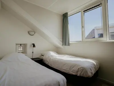 two beds in a room with a window at Oostergeest in Uitgeest
