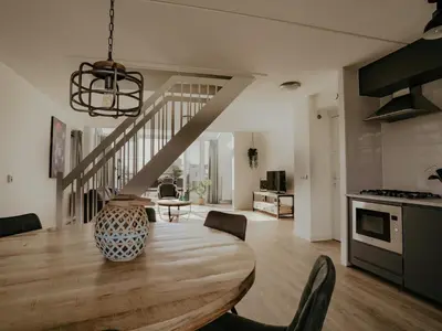 a kitchen and dining room with a table and a staircase at Oostergeest in Uitgeest