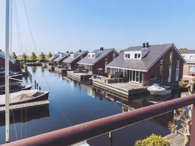 a group of houses on a river with boats at Oostergeest in Uitgeest