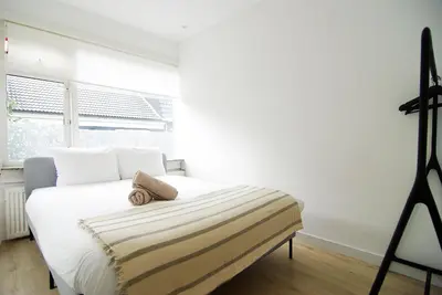 a bedroom with a bed with white sheets and a window at spacious new appartment in Lisse