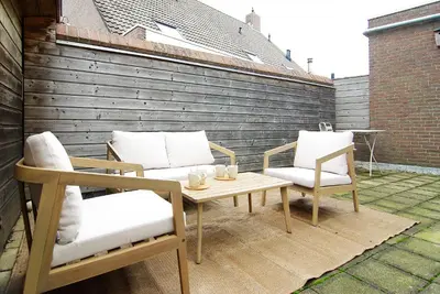 a patio with two chairs and a wooden table and chairs at spacious new appartment in Lisse