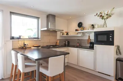 a kitchen with white cabinets and a table with chairs at Garden House Harry in Zandvoort