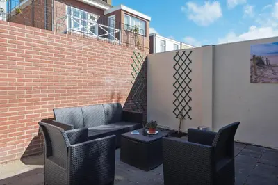 a patio with chairs and a table and a brick wall at Garden House Harry in Zandvoort
