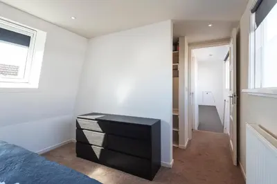 a bedroom with a black dresser and a window at Garden House Harry in Zandvoort