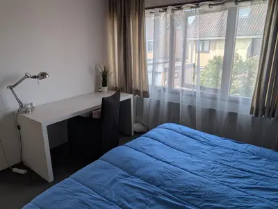 a bedroom with a bed and a desk and a window at 1-2 P Room near Airport AMS freeparking in Roelofarendsveen