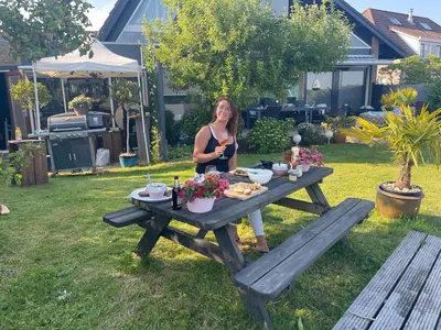 a woman sitting at a picnic table in a yard at 1-2 P Room near Airport AMS freeparking in Roelofarendsveen