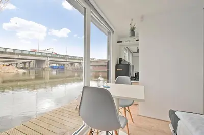 a room with a table and chairs and a large window at HouseBoat the New Lake - Nieuwe Meer in Amsterdam