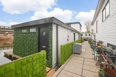 a building with a green hedge next to a house at HouseBoat the New Lake - Nieuwe Meer in Amsterdam