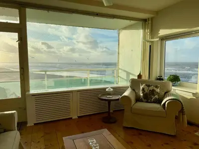 a living room with a large window with a view of the ocean at Blue Bay Zandvoort in Zandvoort