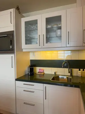 a kitchen with white cabinets and a sink at Blue Bay Zandvoort in Zandvoort