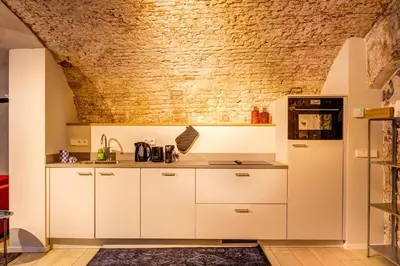 a kitchen with white cabinets and a brick wall at Beautiful canal apartment in Utrecht for 4 persons in Utrecht