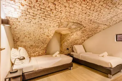 two beds in a room with a stone wall at Beautiful canal apartment in Utrecht for 4 persons in Utrecht