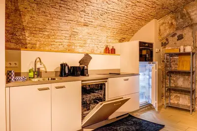 a kitchen with white cabinets and a brick wall at Beautiful canal apartment in Utrecht for 4 persons in Utrecht