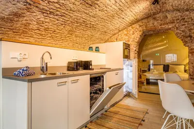 a kitchen with white cabinets and a brick wall at Luxurious canal apartment in Utrecht A Location in Utrecht