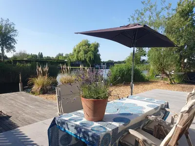 a table with an umbrella and a potted plant on it at Rustic Lake House in Vinkeveen