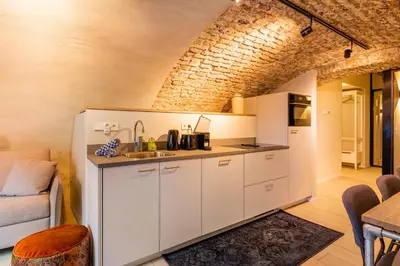 a kitchen with white cabinets and a brick wall at 4P Unique canal apartment A Location in Utrecht in Utrecht