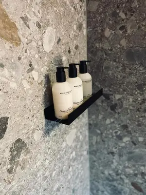 three shampoo bottles sitting on a shelf on a wall at LeLou in Utrecht